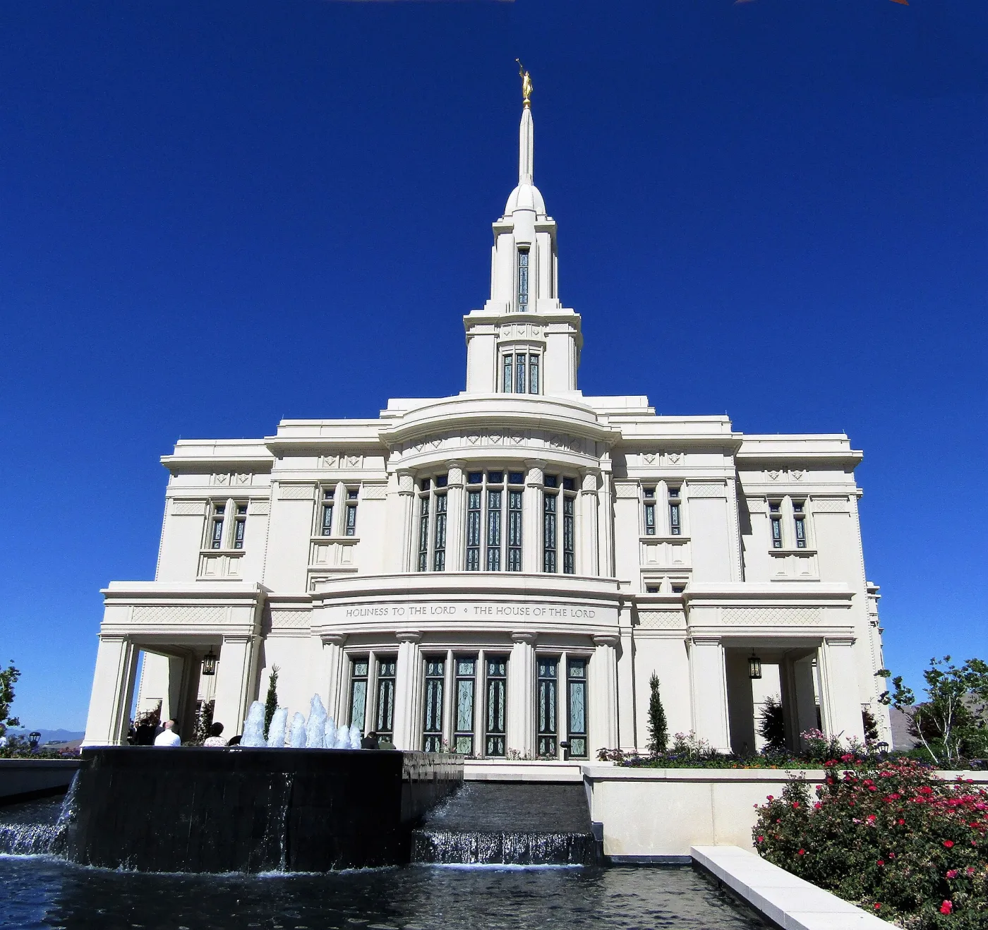 The Payson Utah Temple, with its fountain and rose gardens, under a clear blue sky